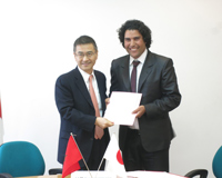 Cérémonie de signature des contrats de dons pour les projets de l'Aide non-remboursable aux micro-projets locaux contribuant à la sécurité humaine (25/03/2015) - l'Ambassadeur Kurokawa remettant le contrat au représentant de l'Association Al Waha pour le développement Ichmarine