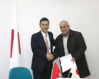 Cérémonie de signature des contrats de dons pour les projets de l'Aide non-remboursable aux micro-projets locaux contribuant à la sécurité humaine (25/03/2015) - l'Ambassadeur Kurokawa remettant le contrat au représentant de la Coopérative Rachad Amzaz