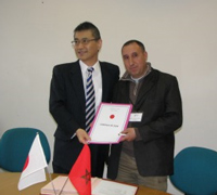 Cérémonie de signature des contrats de dons pour les projets de l'Aide non-remboursable aux micro-projets locaux contribuant à la sécurité humaine (04/03/2016) - l'Ambassadeur Kurokawa remettant le contrat au représentant de l'Association Imoula pour l’environnement et le développement